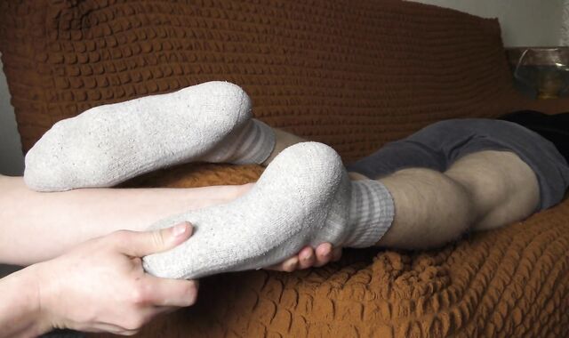 a guy makes a foot massage to a guy in socks - ARTEM SUCHKOV