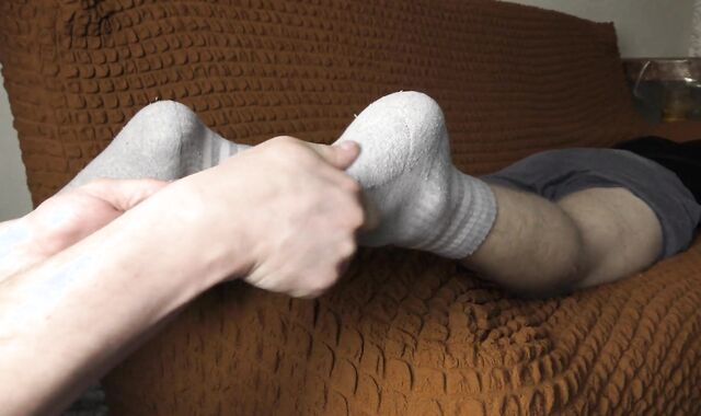 a guy makes a foot massage to a guy in socks - ARTEM SUCHKOV
