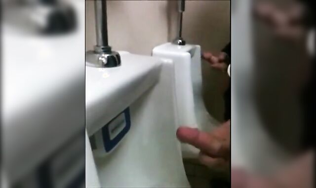 two slim dicks getting wanked at the urinals