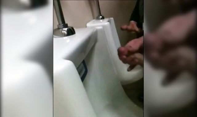 two slim dicks getting wanked at the urinals